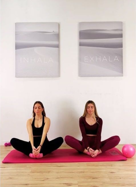 Dos mujeres practicando Pilates y mindfulness con conciencia de la respiración en centro de bienestar en Barcelona